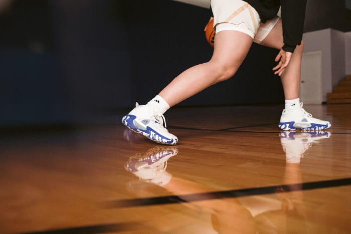 Hailey Van Lith models white and blue adidas basketball shoes.